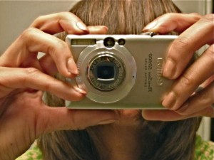 A photo of me with a digital point and shoot camera blocking my face. 